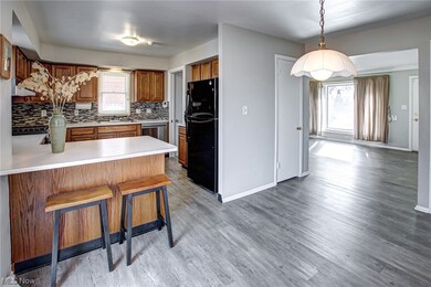 Kitchen featuring black refrigerator, backsplash, hanging light fixtures, light hardwood / wood-style floors, and sink