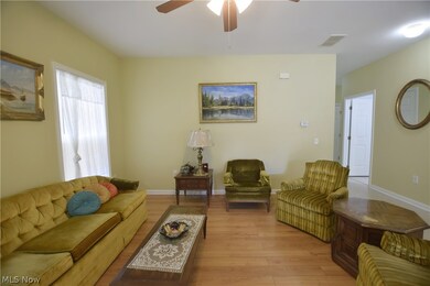 Living room with ceiling fan and hardwood / wood-style flooring