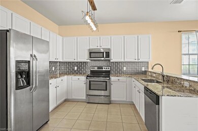Kitchen with white cabinetry, sink, hanging light 