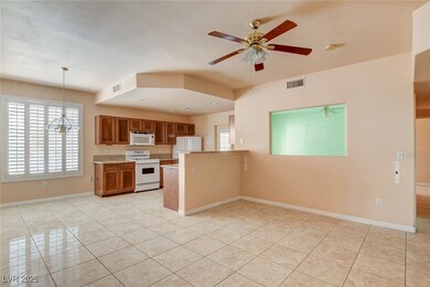 Kitchen with brown cabinets, white appliances, pendant lighting, and light tile patterned floors