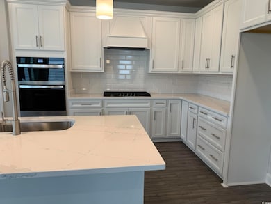 Kitchen with a sink, stainless steel gas stovetop, and white cabinets