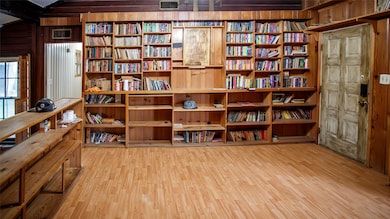 Living area with wall of books, light wood-style floors, and wooden walls