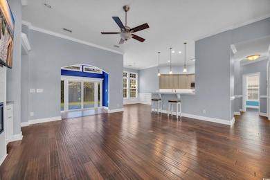 Living room featuring dark wood-style flooring, ceiling fan, crown molding, and recessed lighting