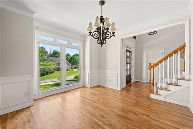 Unfurnished dining area with a chandelier, stairway, wood finished floors, a wainscoted wall, and ornamental molding