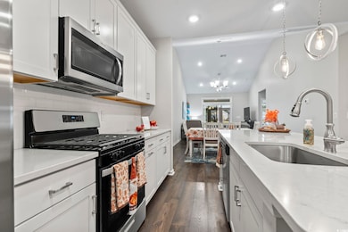 Kitchen featuring appliances with stainless steel finishes, lofted ceiling, recessed lighting, white cabinets, and dark wood finished floors