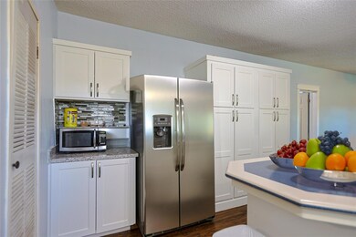 Kitchen featuring stainless steel appliances, white cabinetry, a textured ceiling, dark wood-style flooring, and decorative backsplash