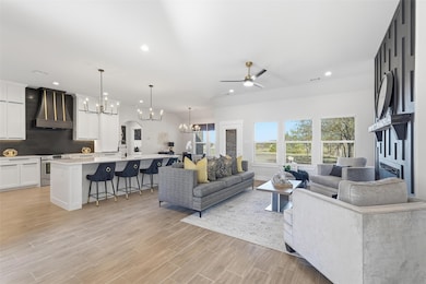 Living area featuring a chandelier, ceiling fan, arched walkways, wood finish floors, and recessed lighting