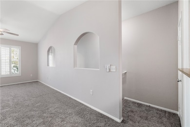 Carpeted spare room featuring ceiling fan and loft