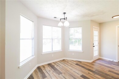 Unfurnished dining area with baseboards, a healthy amount of sunlight, wood finished floors, and visible vents