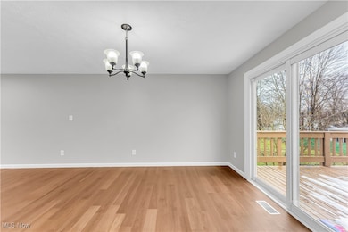 Spare room with an inviting chandelier and light hardwood / wood-style flooring