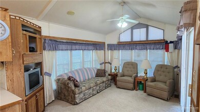 Living room featuring light carpet, ceiling fan, and vaulted ceiling