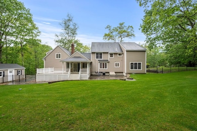 Covered back porch and large deck overlooking the lush green grass and wooded lot