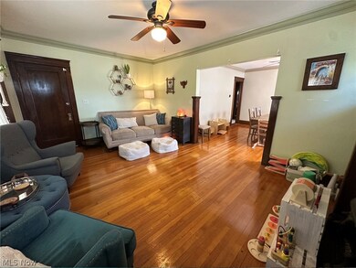 Living room featuring ornamental molding, wood-type flooring, and ceiling fan