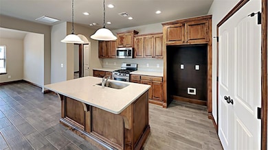 Kitchen with appliances with stainless steel finishes, a sink, baseboards, light countertops, and recessed lighting
