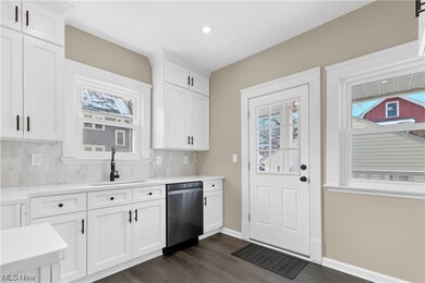 Kitchen with white cabinets, sink, dishwasher, and backsplash
