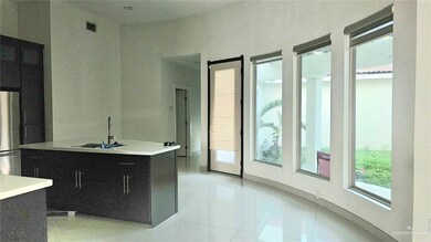 Kitchen with light countertops, dark cabinets, light tile patterned floors, freestanding refrigerator, and modern cabinets