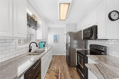 Kitchen with black appliances, white cabinets, sin