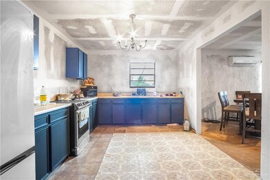 Kitchen with blue cabinetry, freestanding refrigerator, a chandelier, stainless steel range with electric stovetop, and light countertops