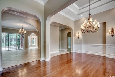 Unfurnished dining area with a chandelier, crown molding, light wood-style floors, and arched walkways