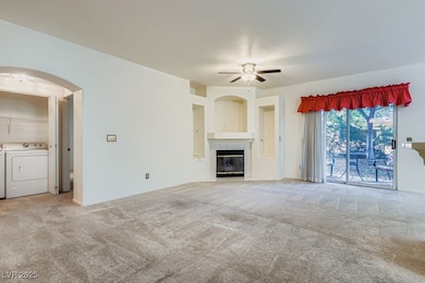 Unfurnished living room with light colored carpet, a tiled fireplace, ceiling fan, and arched walkways