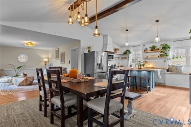 Dining space with light wood-type flooring, healthy amount of natural light, and a wainscoted wall