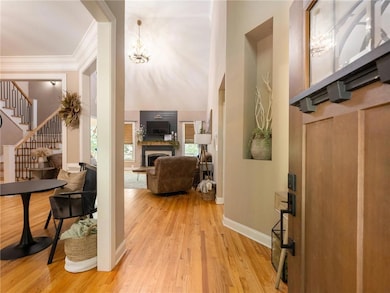 Entrance foyer with stairway, light wood finished floors, ornamental molding, a fireplace with raised hearth, and a chandelier