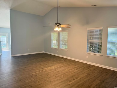 Spare room with ceiling fan, vaulted ceiling, dark wood-style flooring, and baseboards