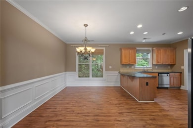 Kitchen with dishwasher, a chandelier, a peninsula, dark countertops, and a sink