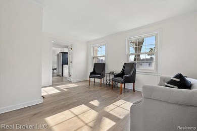 Living area with crown molding, light wood-style floors, and plenty of natural light