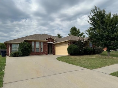 Single story home featuring a garage, driveway, a front yard, and brick siding