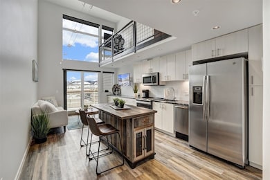 Kitchen includes a high ceiling, light wood-style