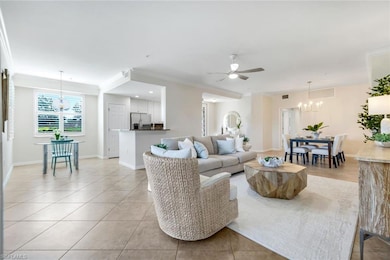 Living area featuring ornamental molding, light tile patterned floors, a chandelier, a ceiling fan, and baseboards