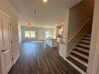Kitchen with dark wood-type flooring, white cabinets, and ceiling fan