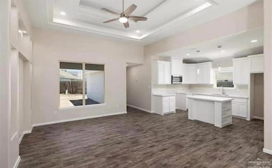 Kitchen with stainless steel microwave, dark wood-type flooring, a sink, a center island, and ceiling fan