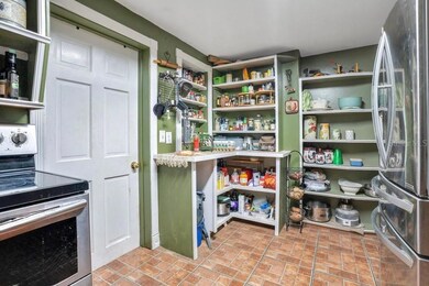 True to the home’s timeless character, the generous Kitchen offers open shelving at both ends—an inviting nod to its storied past, blending classic style with everyday practicality.