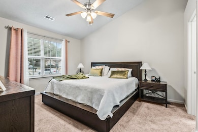Bedroom featuring light carpet, vaulted ceiling, a
