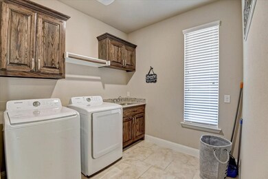 Washroom featuring washing machine and dryer, cabinet space, and light tile patterned floors