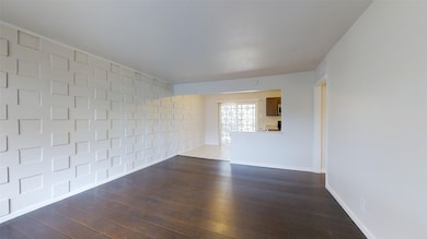 Spare room with dark wood-type flooring and baseboards