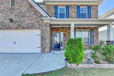 Doorway to property with brick siding, a porch, an attached garage, and driveway