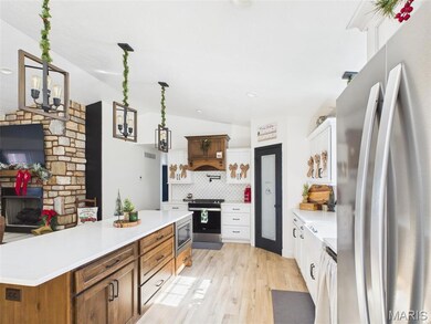 Kitchen with appliances with stainless steel finishes, white cabinets, light wood-style flooring, brown cabinets, and vaulted ceiling