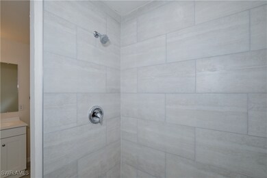 Bathroom featuring tiled shower and vanity