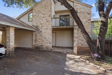 View of front of house featuring a balcony, stone siding, and a shingled roof