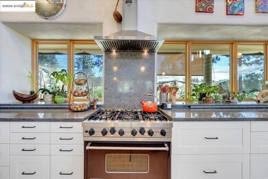 Kitchen featuring high end range, island range hood, white cabinetry, and dark stone counters