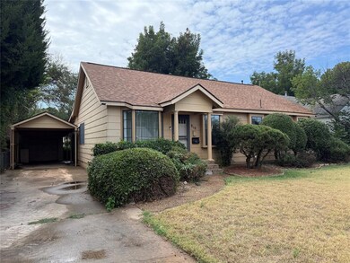 Ranch-style house featuring an outdoor structure, a shingled roof, a front lawn, a carport, and driveway