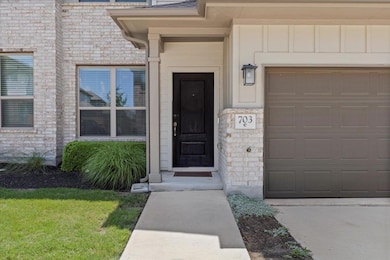 Entrance to property with board and batten siding, a garage, driveway, and stone siding