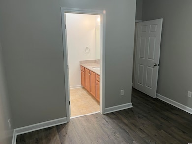 Unfurnished bedroom featuring wood finished floors, baseboards, and ensuite bathroom
