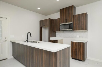 Kitchen with stainless steel microwave, modern cabinets, a sink, light marble finish floors, and recessed lighting