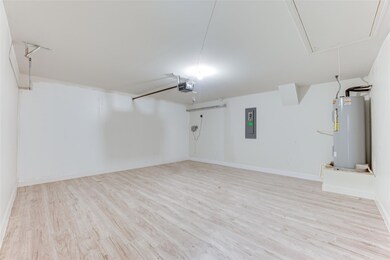 Garage featuring baseboards, electric panel, elect