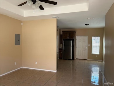 Unfurnished room featuring electric panel, a ceiling fan, light tile patterned floors, and a raised ceiling