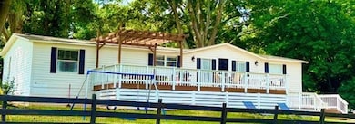 Frony view of property with a pergola, a deck, and a lawn